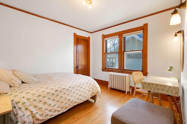 bedroom featuring crown molding, radiator heating unit, and wood-type flooring