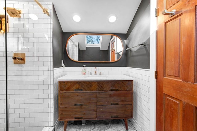 bathroom featuring walk in shower, vanity, and tile walls