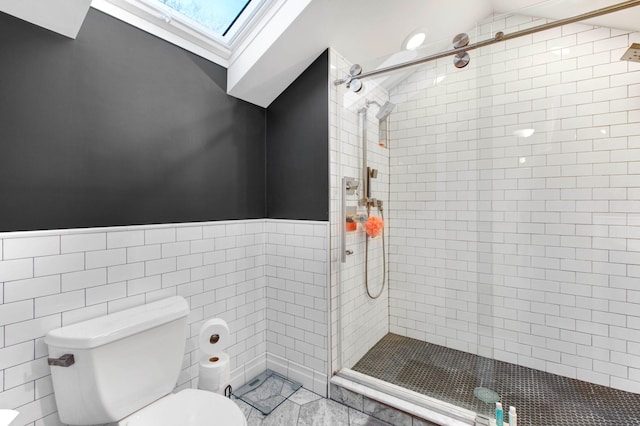 bathroom with a skylight, toilet, an enclosed shower, and tile walls