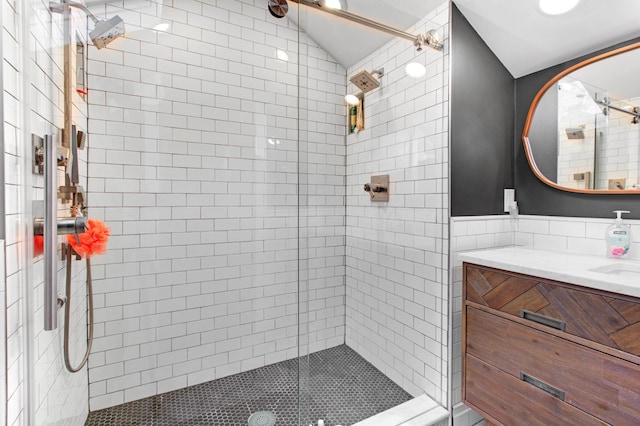 bathroom with an enclosed shower, vanity, and tile walls