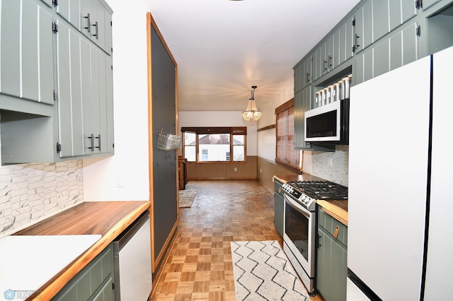 kitchen with appliances with stainless steel finishes, tasteful backsplash, an inviting chandelier, light parquet flooring, and hanging light fixtures