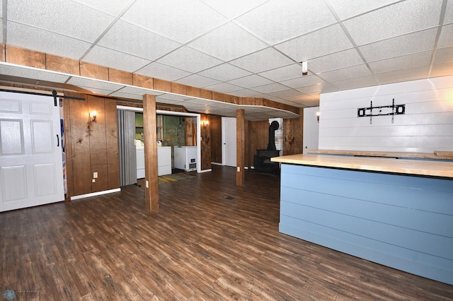 kitchen featuring a barn door, wood walls, dark hardwood / wood-style flooring, and a paneled ceiling