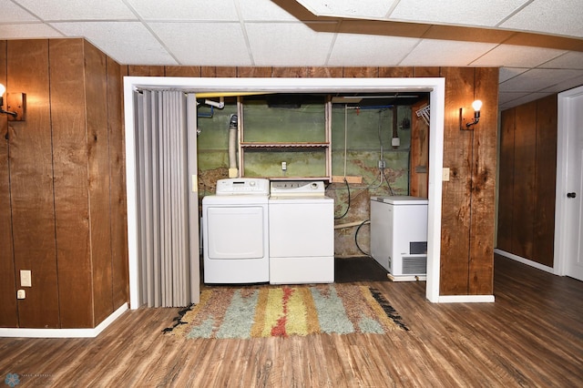 clothes washing area featuring wood walls, dark hardwood / wood-style flooring, and independent washer and dryer