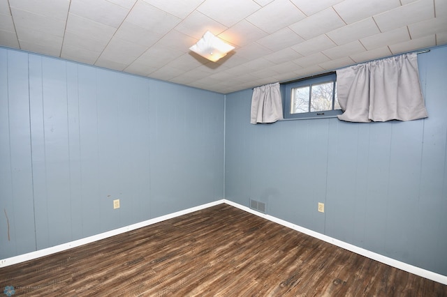 unfurnished room with wood-type flooring and wooden walls