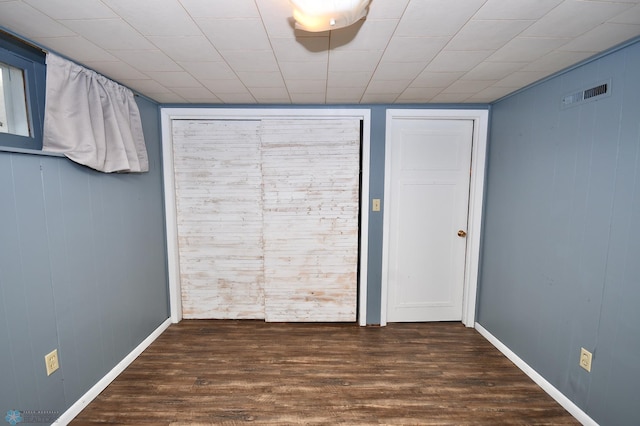 unfurnished bedroom featuring wood walls and dark wood-type flooring