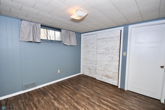 unfurnished bedroom with dark hardwood / wood-style flooring and wooden walls