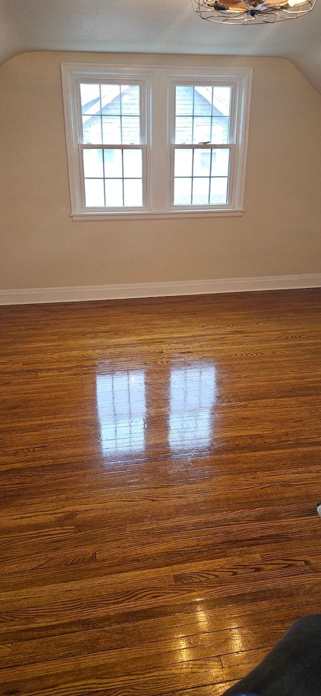 empty room with dark hardwood / wood-style flooring and lofted ceiling