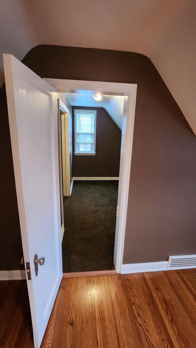 corridor featuring wood-type flooring and vaulted ceiling