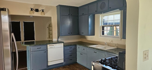 kitchen featuring dishwasher, sink, kitchen peninsula, range, and stainless steel refrigerator