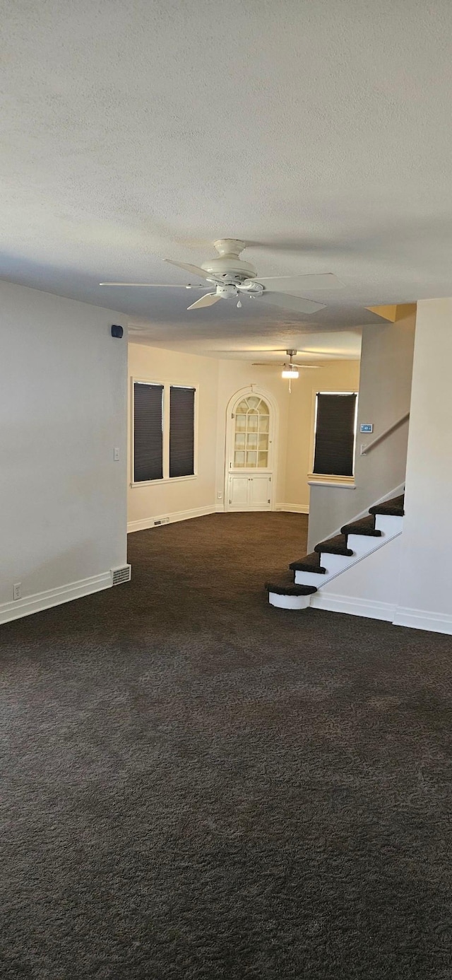 carpeted empty room featuring ceiling fan and a textured ceiling