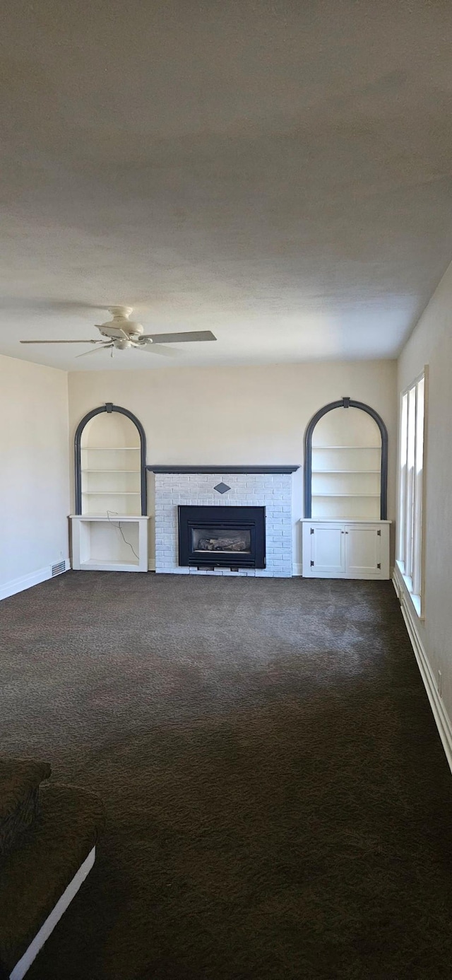 unfurnished living room featuring carpet, ceiling fan, and a tiled fireplace