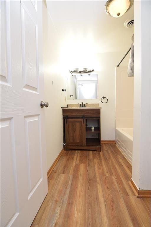 bathroom featuring hardwood / wood-style floors, vanity, and shower / bathtub combination