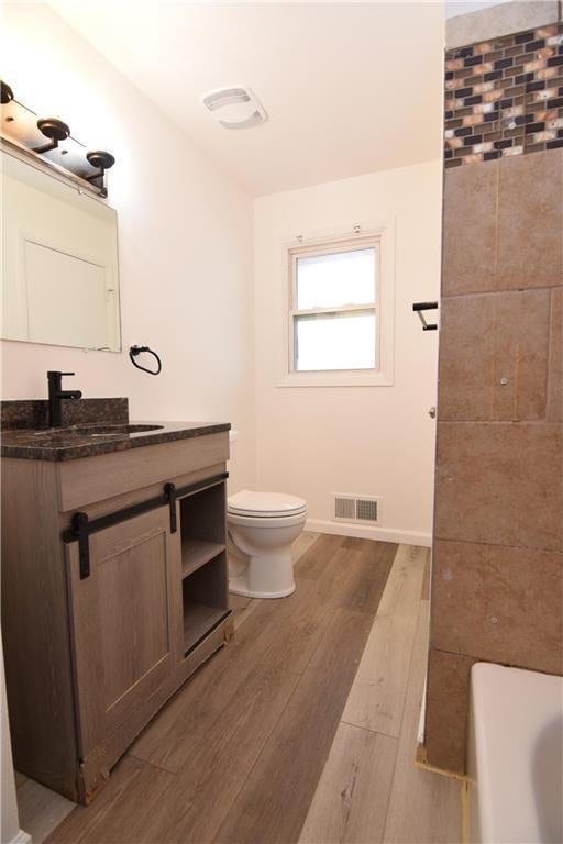 bathroom featuring a bathtub, toilet, vanity, and hardwood / wood-style flooring