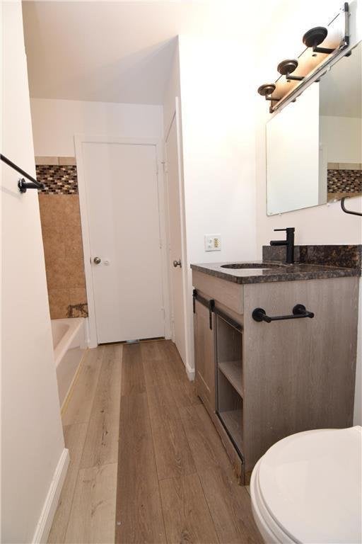 full bathroom with bathtub / shower combination, vanity, hardwood / wood-style flooring, and toilet