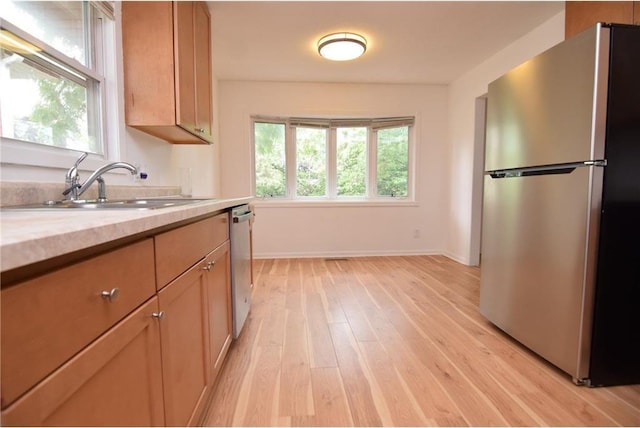 kitchen with appliances with stainless steel finishes, light hardwood / wood-style floors, and sink