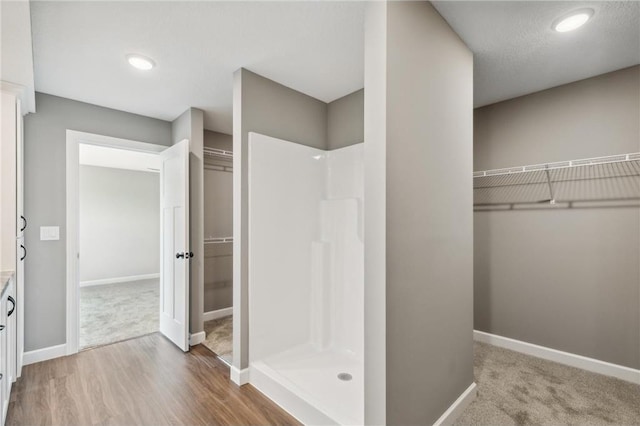 bathroom with hardwood / wood-style floors, a textured ceiling, and walk in shower