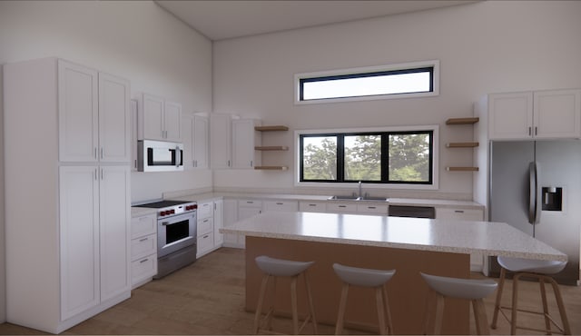 kitchen featuring stainless steel appliances, a kitchen island, white cabinetry, and a breakfast bar area