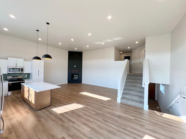 kitchen featuring recessed lighting, light wood finished floors, a center island, and appliances with stainless steel finishes