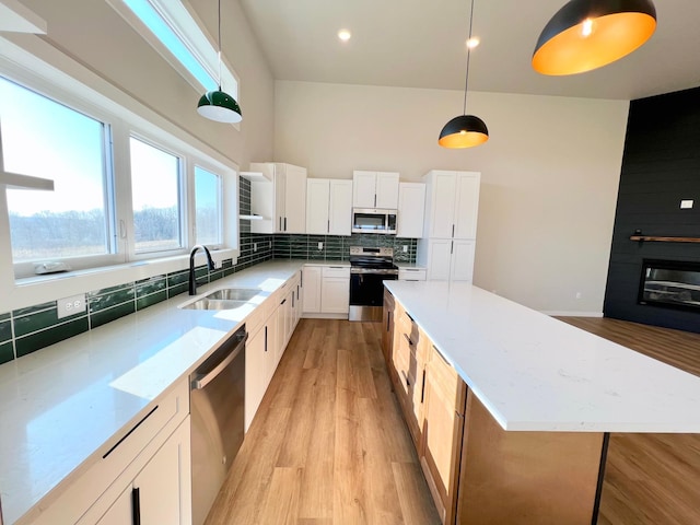 kitchen with tasteful backsplash, light wood-type flooring, a center island, a sink, and stainless steel appliances