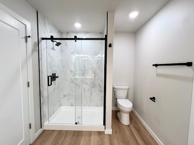 bathroom featuring a marble finish shower, baseboards, toilet, and wood finished floors