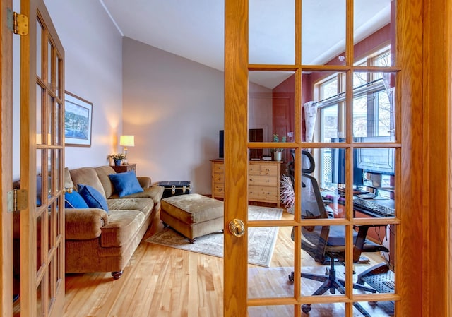 living room with hardwood / wood-style flooring, vaulted ceiling, and french doors