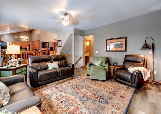 living room with lofted ceiling, hardwood / wood-style flooring, and ceiling fan with notable chandelier