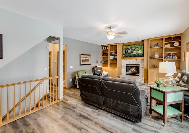 living room featuring ceiling fan, a fireplace, and light hardwood / wood-style flooring