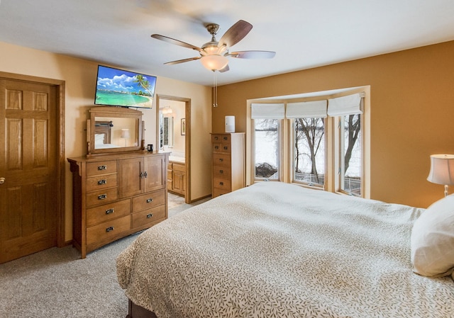 bedroom featuring light carpet, ensuite bath, and ceiling fan