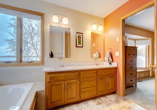 bathroom featuring a healthy amount of sunlight, vanity, and tiled tub