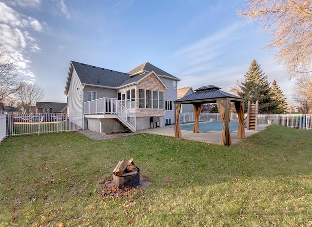 back of house with a patio area, a gazebo, a lawn, an outdoor fire pit, and a sunroom