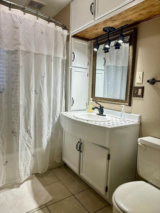 bathroom with tile patterned floors, a shower with curtain, vanity, and toilet