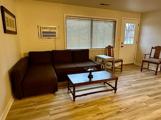 living room with a wall unit AC and light hardwood / wood-style flooring