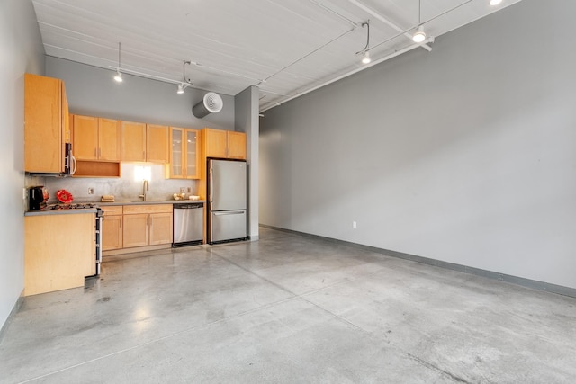 kitchen featuring light brown cabinets, rail lighting, sink, a towering ceiling, and appliances with stainless steel finishes