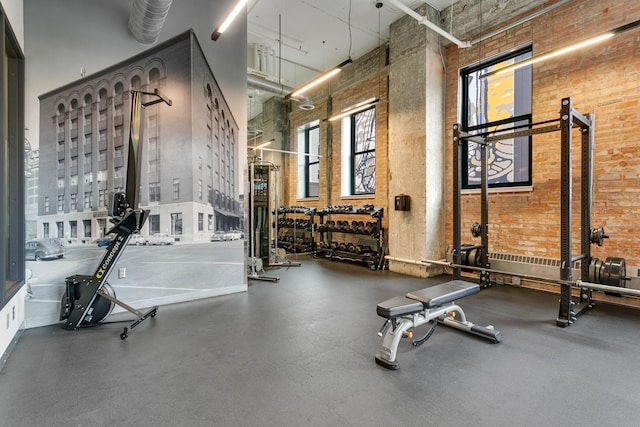 gym with a towering ceiling and brick wall