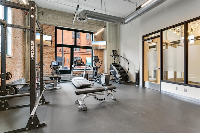 gym featuring a high ceiling and brick wall