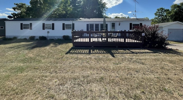 back of house with a yard, an outdoor structure, and a wooden deck