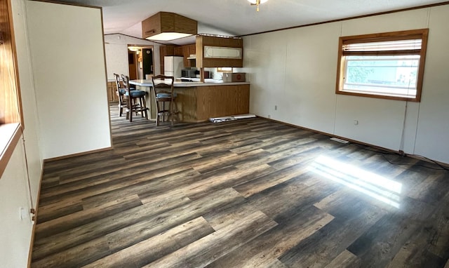 kitchen featuring dark hardwood / wood-style floors, white refrigerator, kitchen peninsula, a textured ceiling, and vaulted ceiling