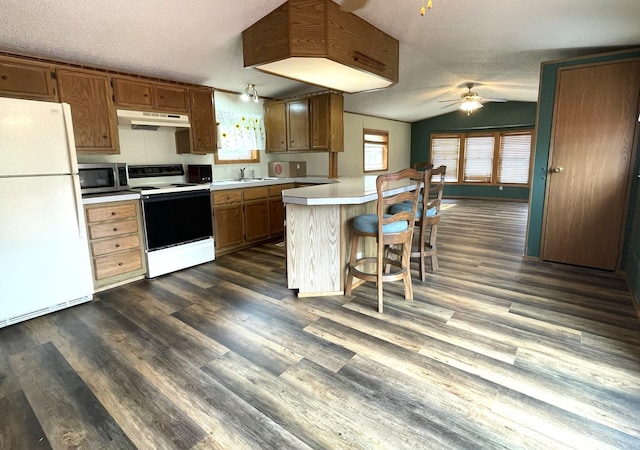 kitchen featuring a kitchen breakfast bar, white appliances, dark hardwood / wood-style flooring, and lofted ceiling