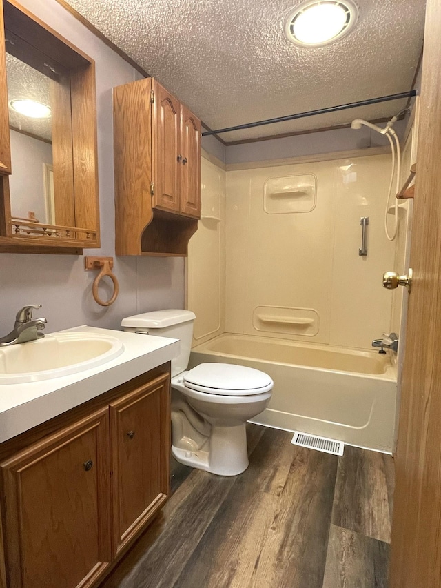 full bathroom with vanity, bathing tub / shower combination, hardwood / wood-style flooring, toilet, and a textured ceiling