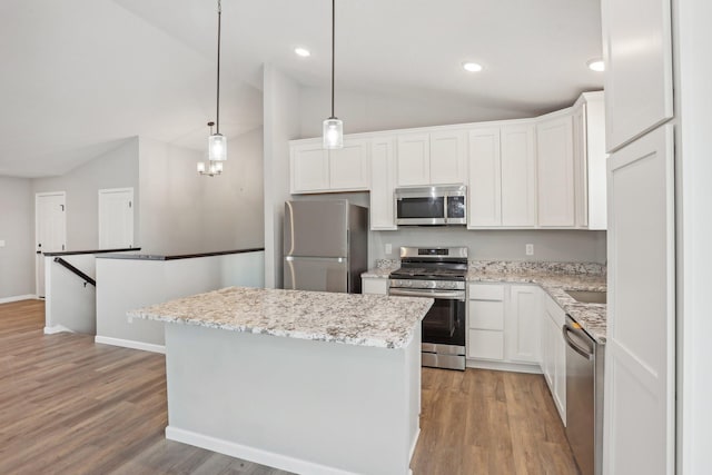 kitchen featuring hanging light fixtures, white cabinets, stainless steel appliances, and lofted ceiling