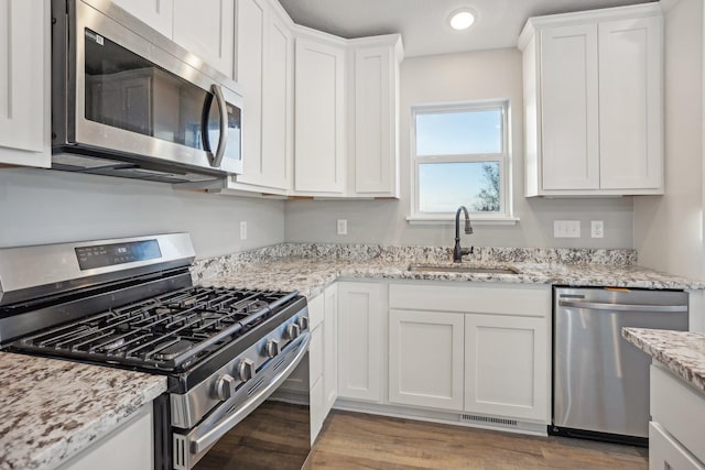 kitchen featuring white cabinetry, sink, stainless steel appliances, and light hardwood / wood-style flooring