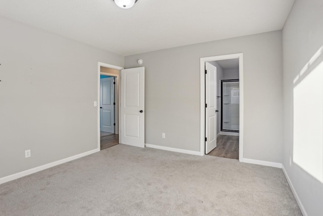 unfurnished bedroom featuring ensuite bath and light colored carpet