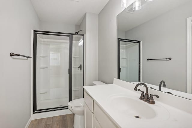 bathroom with hardwood / wood-style flooring, vanity, toilet, and a shower with door