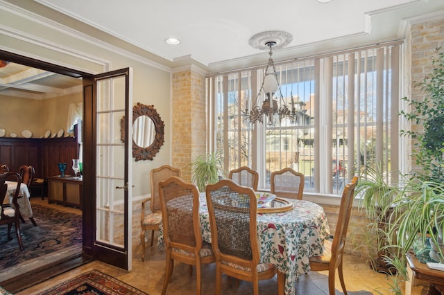 tiled dining room featuring an inviting chandelier, a healthy amount of sunlight, and crown molding