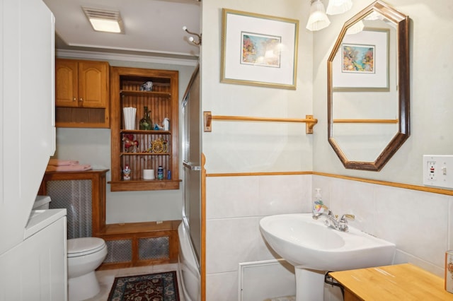 bathroom featuring toilet, tile walls, ornamental molding, and sink