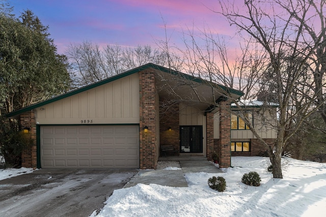 view of front of home featuring a garage, brick siding, and board and batten siding