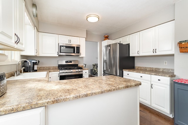 kitchen with stainless steel appliances, a peninsula, a sink, white cabinets, and light countertops