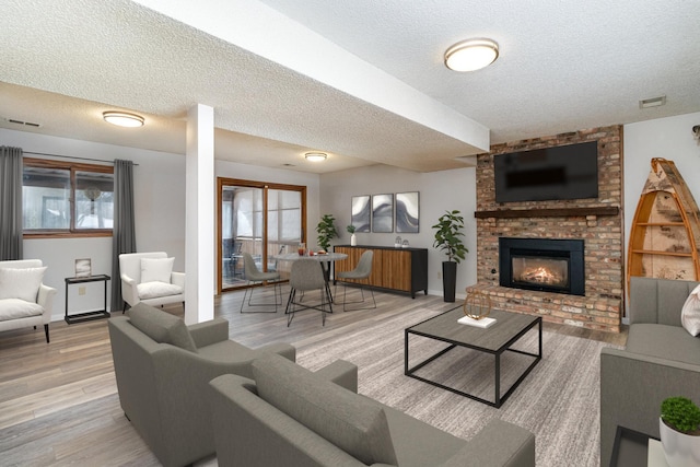 living room featuring light wood-style floors, a brick fireplace, visible vents, and a wealth of natural light