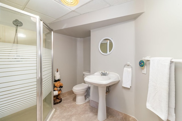 full bathroom featuring a paneled ceiling, a shower stall, toilet, and tile patterned floors