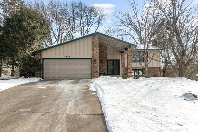 view of front of home with a garage, concrete driveway, and brick siding